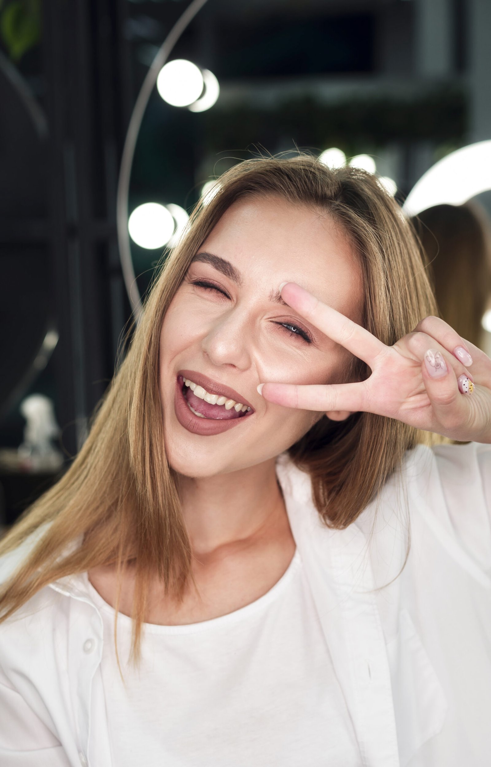 blonde woman smiling doing peace sign scaled