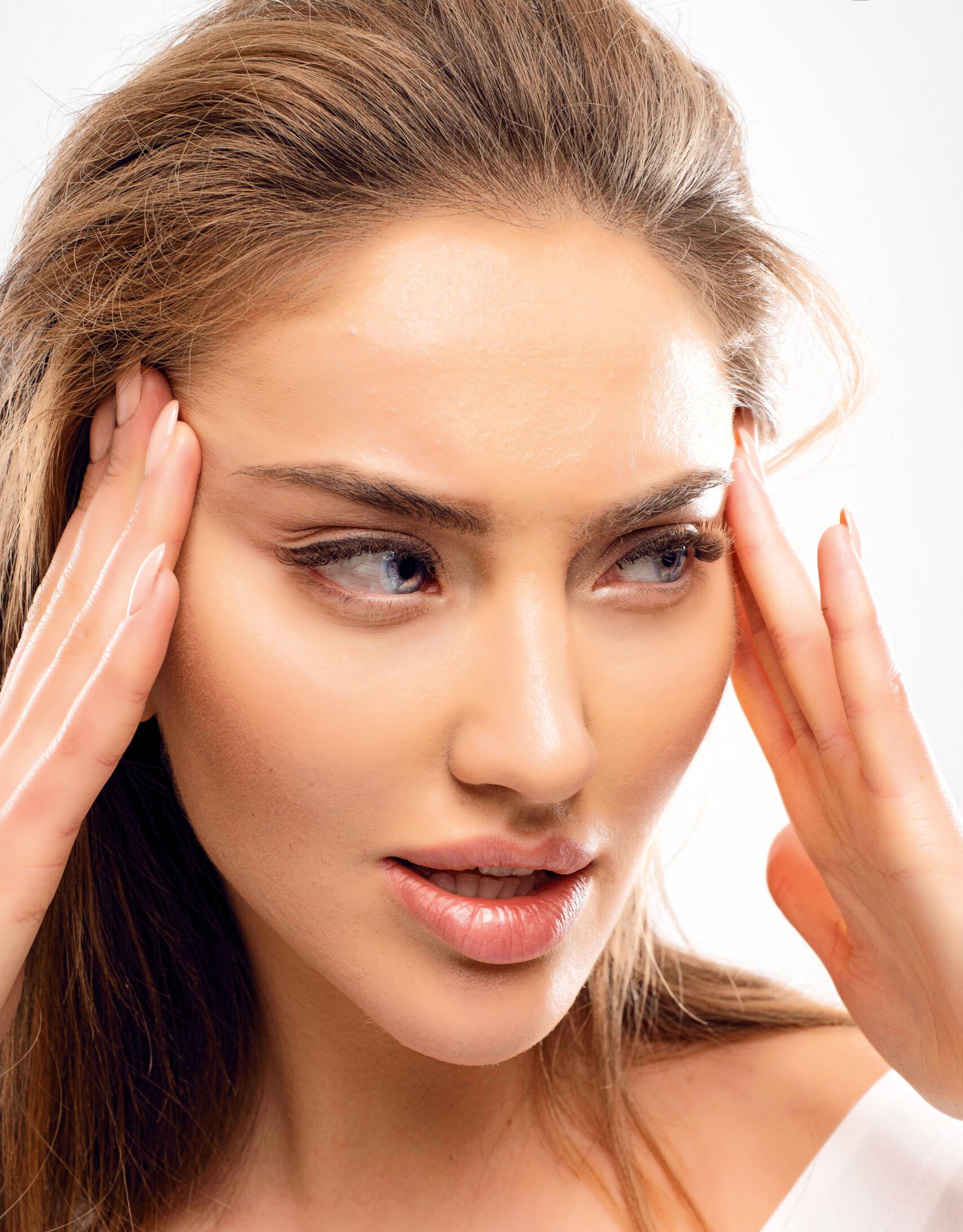 pretty woman holding herself face stretching up skin make her look younger big lips blue eyes looking away volume blonde hairstyle natural makeup scaled e1789646520188