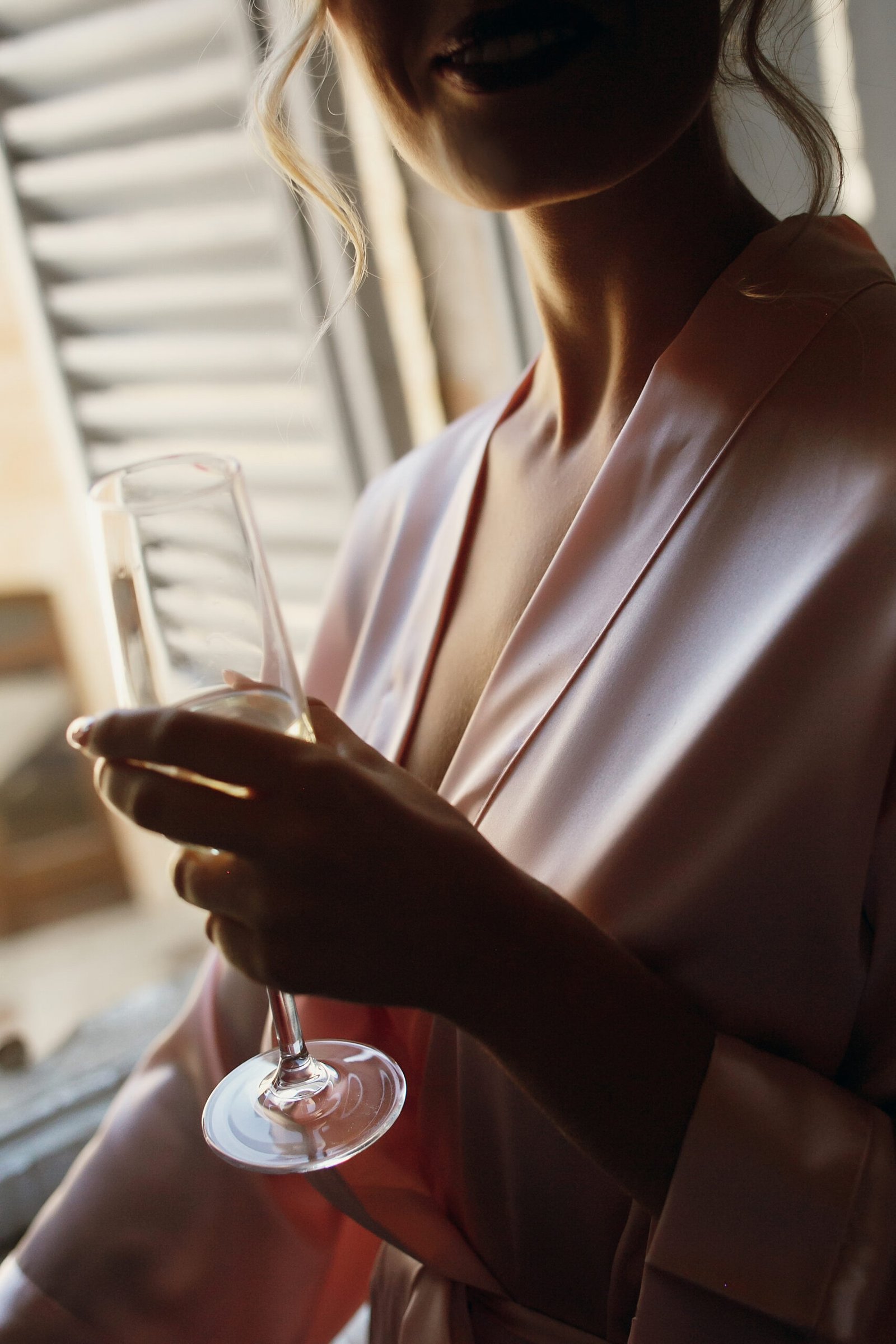seductive lady pink silk robe holds champagne flute scaled