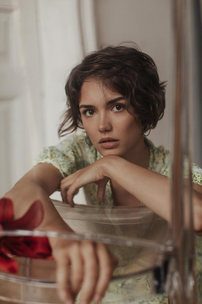 tanned browneyed shorthaired calm woman floral green dress looks into camera leans transparent chair 197531 29898